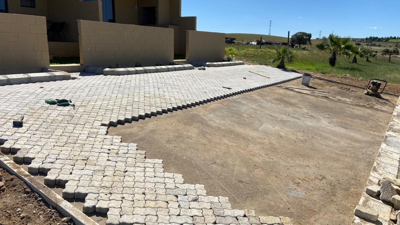 Interlocking pavers part-laid across a prepared base